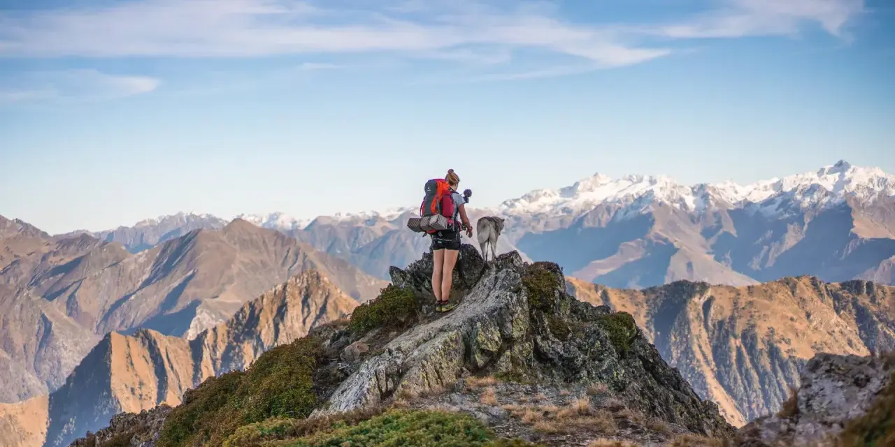 Randonneuse et son chien contemplent les sommets enneigés des Pyrénées-Orientales, un paysage grandiose sur le GR10.