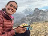 Sourire radieux d'une randonneuse savourant son repas en pleine montagne, avec des sommets enneigés en arrière-plan. Un moment de pur bonheur pour ce repas randonnée.