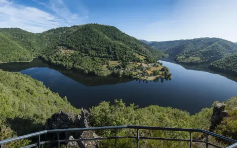 Vue panoramique des gorges de la Truyère, un lac paisible reflétant les collines verdoyantes. Idéal pour la randonnée.