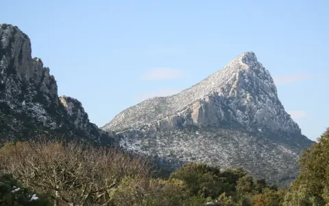 Vue hivernale du pic Saint-Loup, ses pentes couvertes de neige contrastant avec le ciel bleu.
