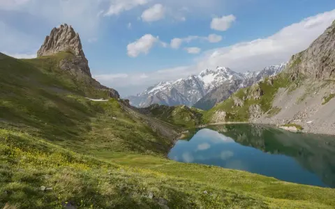 Magnifique lac alpin reflétant les montagnes enneigées, idéal pour une randonnée près de Briançon.
