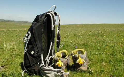 Sac à dos et chaussures de randonnée ornées de jonquilles, prêts pour une randonnée sur l'Aubrac.