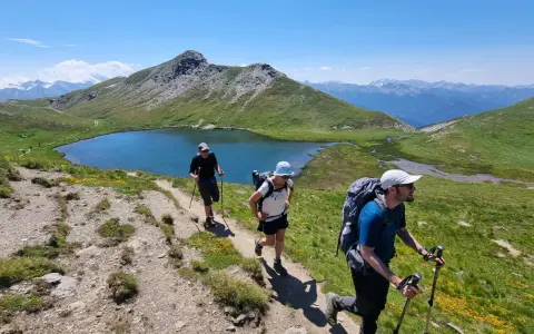 Trois randonneurs progressent sur un sentier de montagne, profitant d'un paysage spectaculaire. Ils sont en plein tour du Queyras 4 jours.