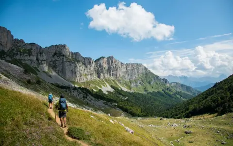 Deux randonneurs explorent un sentier escarpé au Pays Basque, sous un ciel bleu et des falaises imposantes.