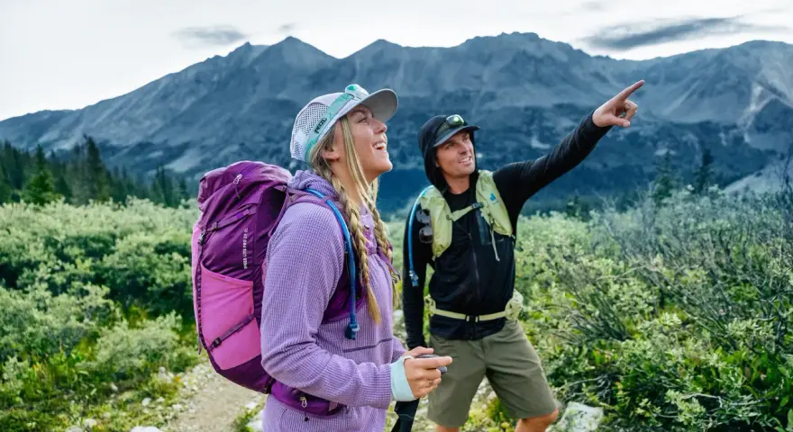 Deux randonneurs s'émerveillent devant un panorama de amm montagne. L'un d'eux pointe du doigt un sommet lointain.