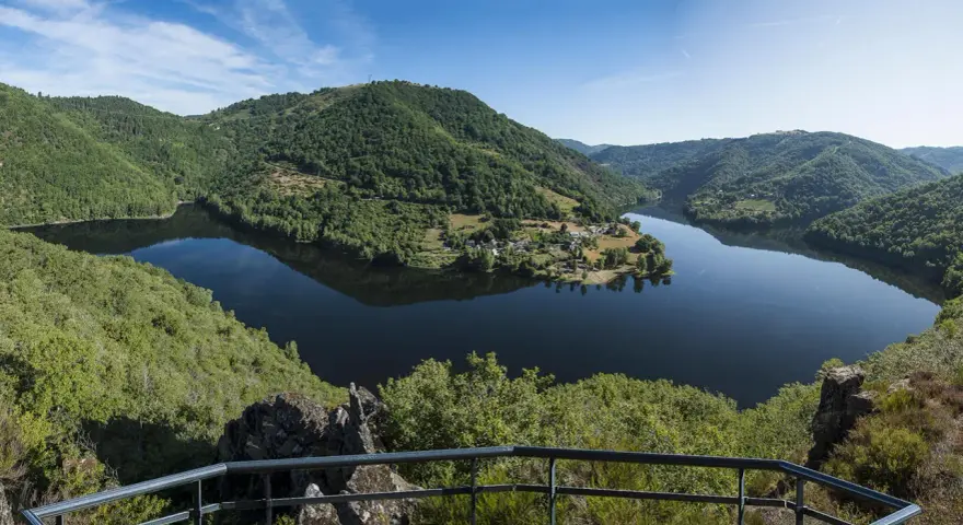 Vue panoramique des gorges de la Truyère, un lac paisible reflétant les collines verdoyantes. Idéal pour la randonnée.