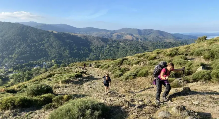 Des randonneurs progressent sur un sentier rocailleux, profitant d'une vue panoramique sur les montagnes verdoyantes lors d'une randonnée au Mont Aigoual.