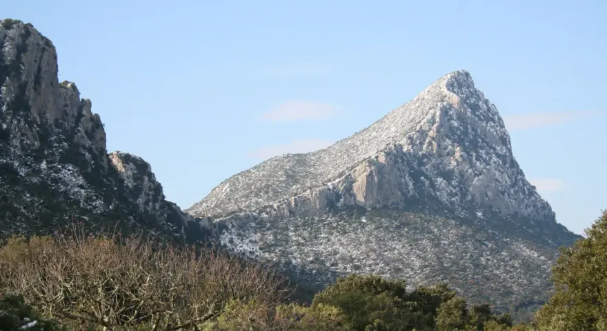 Vue hivernale du pic Saint-Loup, ses pentes couvertes de neige contrastant avec le ciel bleu.