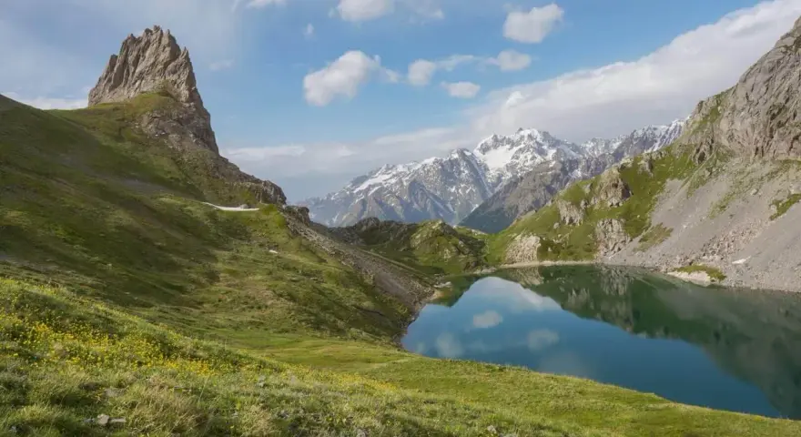 Magnifique lac alpin reflétant les montagnes enneigées, idéal pour une randonnée près de Briançon.