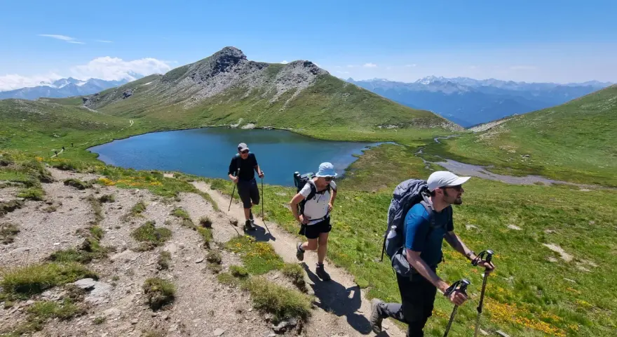 Trois randonneurs progressent sur un sentier de montagne, profitant d'un paysage spectaculaire. Ils sont en plein tour du Queyras 4 jours.