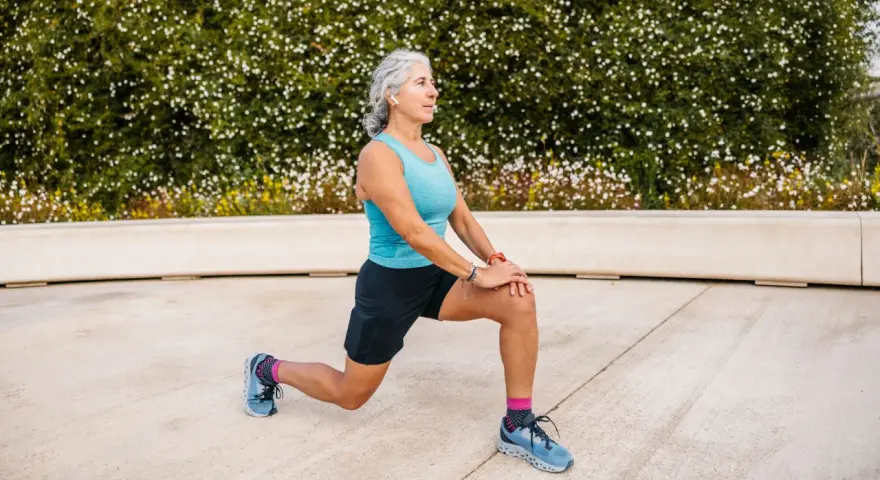 Femme âgée faisant un étirement des jambes, préparation pour un échauffement pieds randonnée.