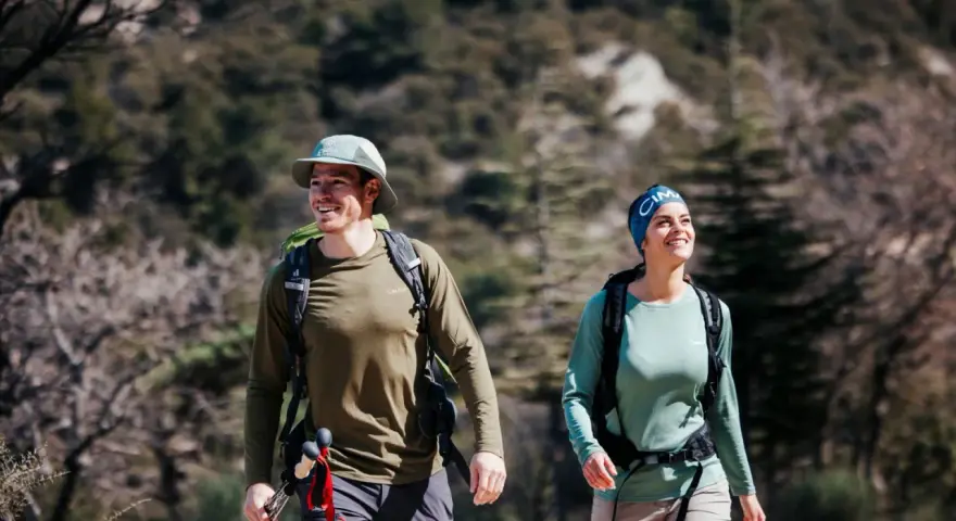 Randonneurs souriants malgré la chaleur, le mal de tête guette peut-être. Ils marchent sur un sentier rocailleux.