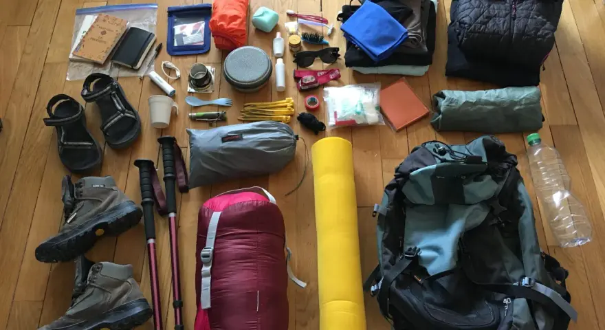 Préparatifs pour une randonnée : chaussures, bâtons, sac de couchage, sac à dos, vêtements, trousse de toilette, gourde. Voici comment ranger son sac de randonnée.