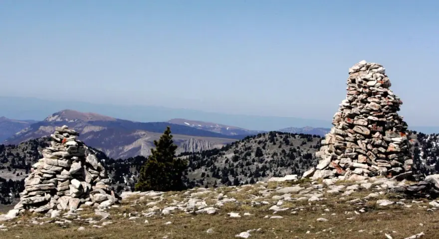 Deux cairns de cailloux marquent le paysage montagneux, offrant des repères visuels sur le sentier.