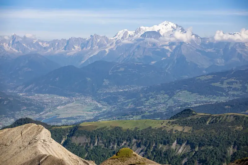 Vue panoramique des Alpes, avec le Mont Blanc enneigé, point culminant des Alpes, dominant la vallée verdoyante et ses villages.